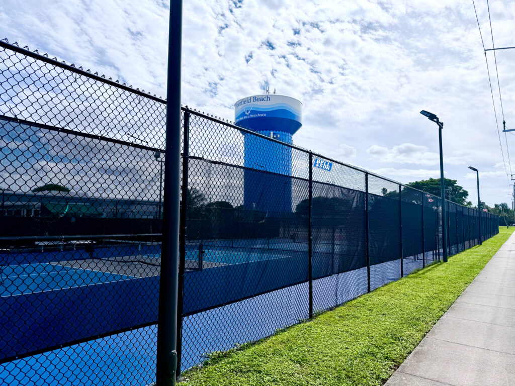 A photo of a heavy-duty, black vinyl-coated chain link fence securing a commercial property.